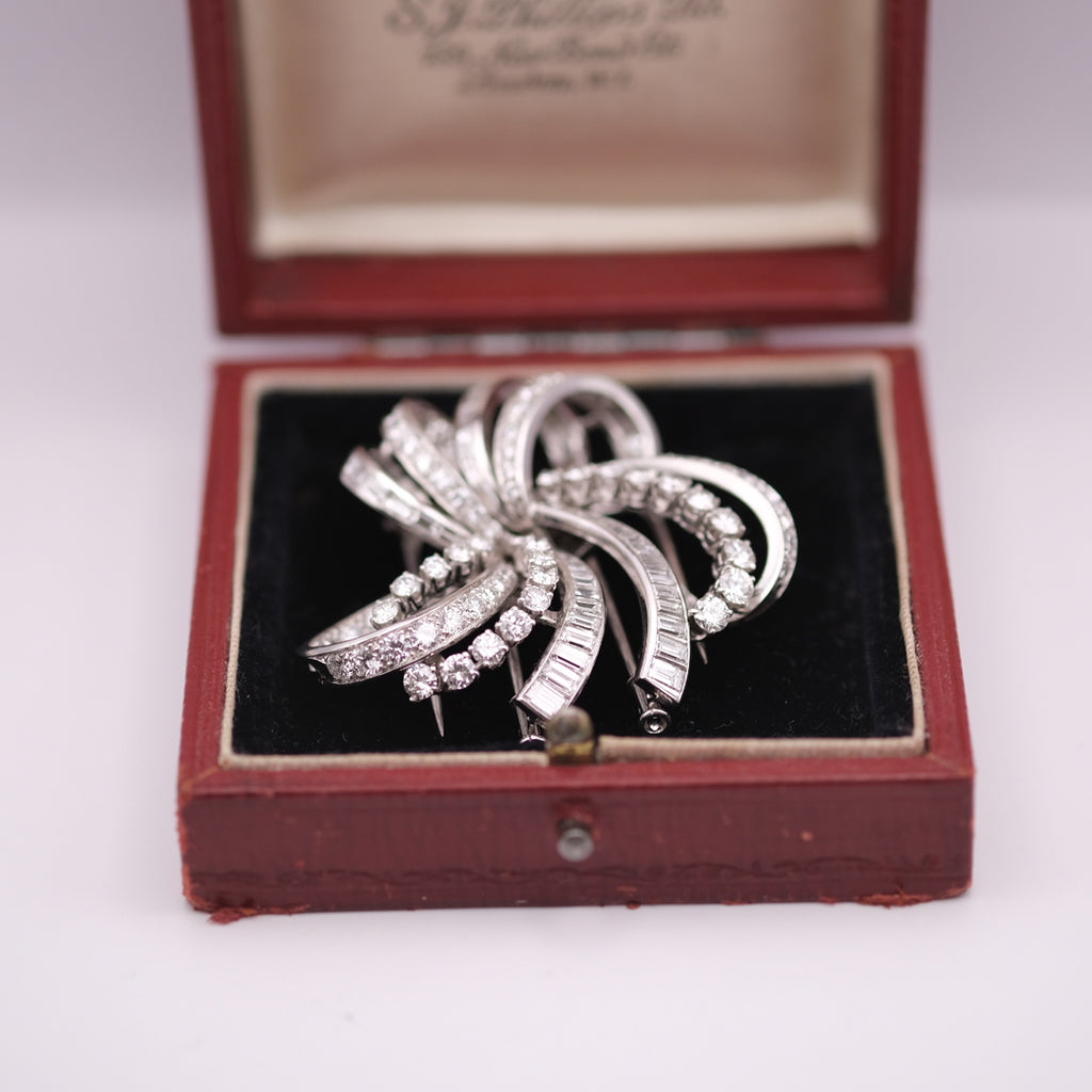 Silver brooch with gemstones in an open red jewelry box on a white background