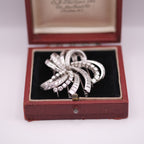 Silver brooch with gemstones in an open red jewelry box on a white background