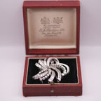 Silver brooch in a red jewelry box with a visible brand logo.
