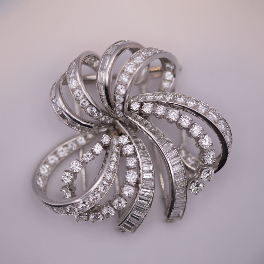 Silver brooch with diamond accents on a light gray background