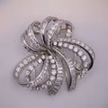 Silver brooch with diamond accents on a light gray background