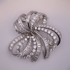 Silver brooch with diamond accents on a light gray background